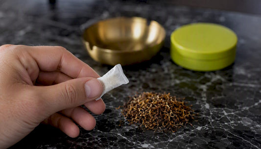 Nicotine pouch held with dipping tobacco pile nearby