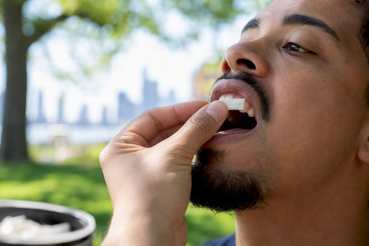 Hand placing nicotine pouch in mouth