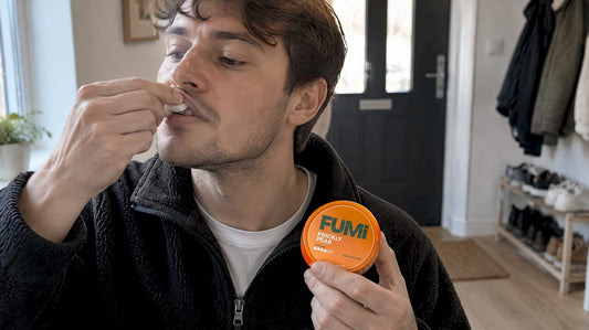 Adult placing a nicotine pouch under upper lip